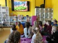 Przedszkolaki oglądają na ekranie telewizora zdjęcie kwiatów