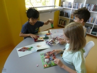 Troje dzieci układa na stoliku klocki LEGO